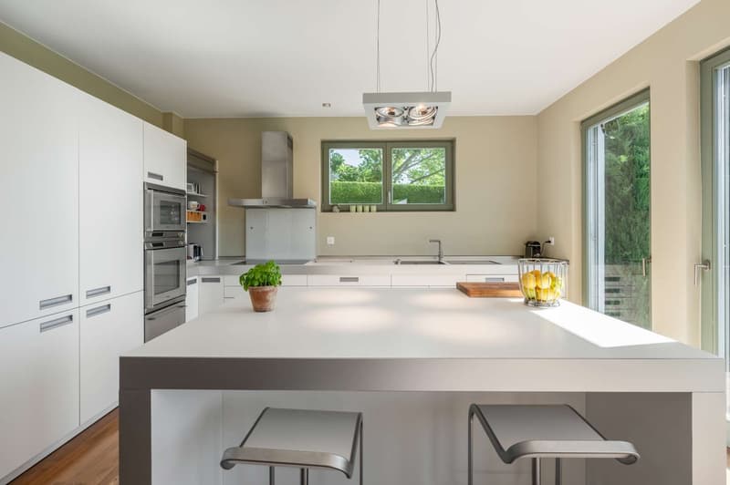 modern white kitchen, central island, stainless steel stove and oven, double sink, sliding glass doors to garden