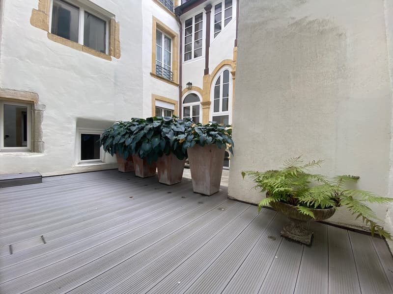 Concrete paved courtyard, white walls, large potted plants, wooden deck