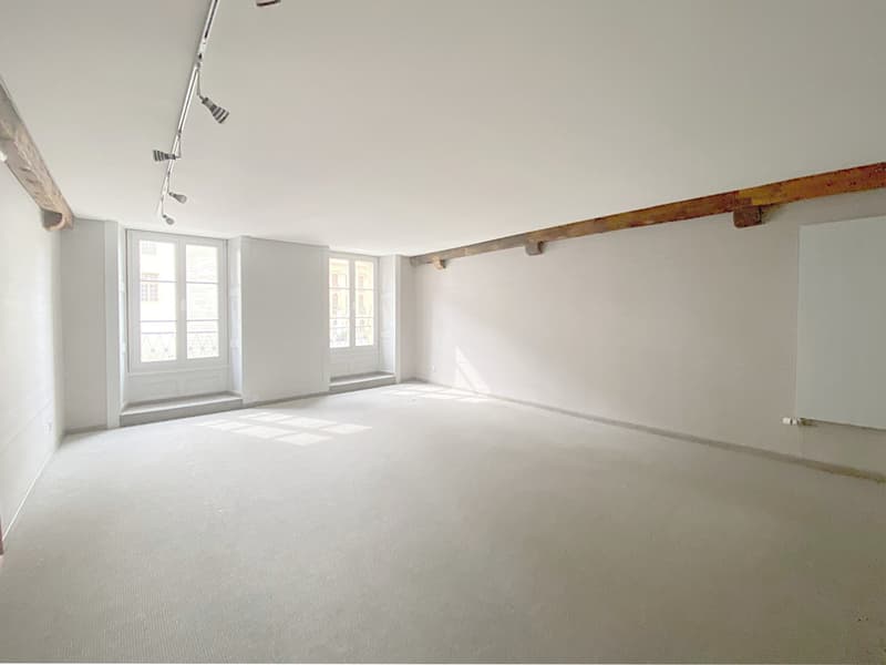 empty room, white walls, exposed ceiling beams, white ceiling, two windows, wooden floors