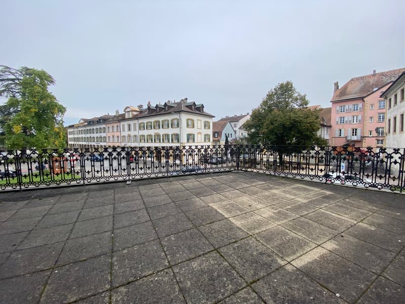 a tiled roof terrace with wrought iron railings and a street view