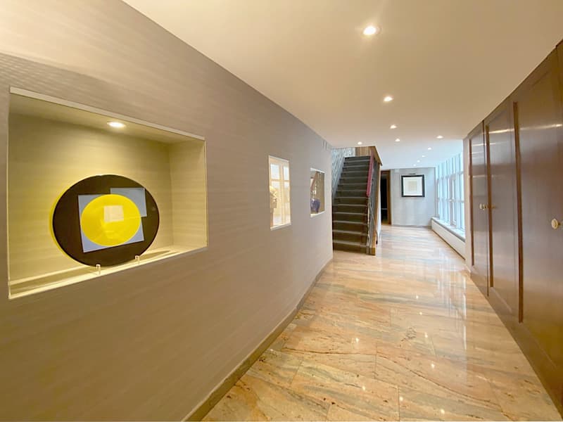 Luxurious hallway, gray walls, decorative circle, marble flooring, wooden staircase, illuminated with ceiling lights