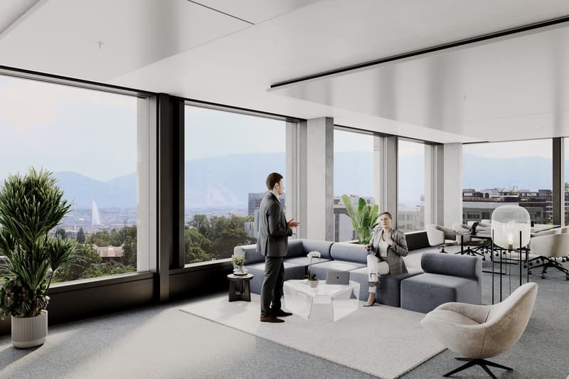 Spacious living room with floor-to-ceiling windows offering a panoramic view of the city skyline. The room features a large gray sectional sofa, a white armchair, and a coffee table. There are also potted plants and other decorative elements. The overall