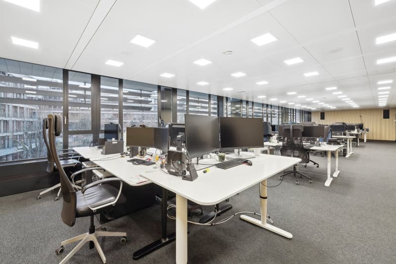 open space office, modern furniture, multiple desks, monitors, glass windows, ceiling lights
