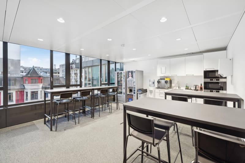 large kitchen table, kitchen cabinets, microwave, refrigerator, garbage bin, sink, chairs, glass windows