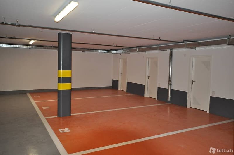 Empty underground parking lot with numbered parking spaces, white and red flooring, three parking stalls visible.