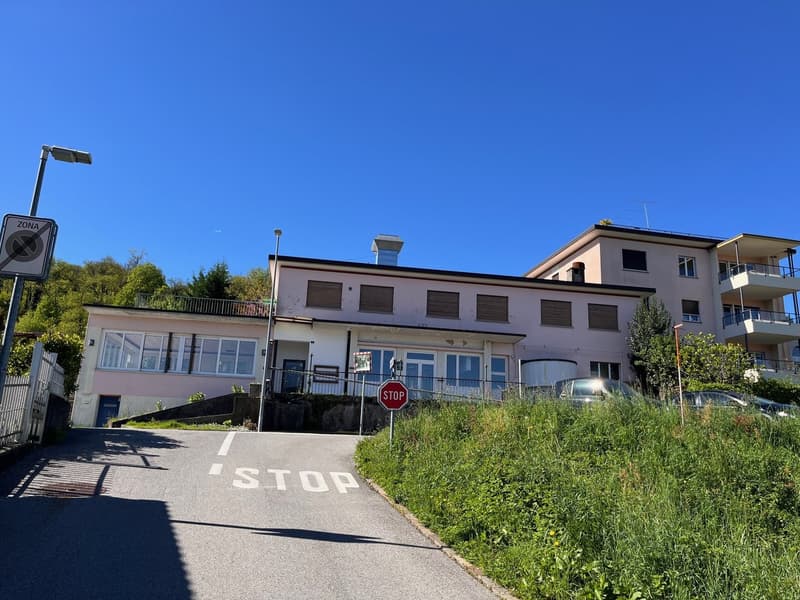 Two-story building with multiple windows, a balcony on the second floor, and a stop sign in front.