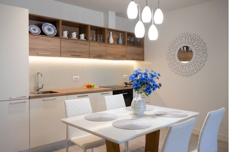 Dining area with table, chairs, modern kitchen, cabinets, dining table, flowers, and power outlets