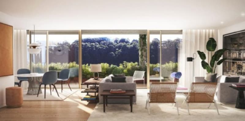 Spacious open-plan living room with large windows overlooking a scenic outdoor view, hardwood floors, modern furniture including a sofa, chairs, and coffee table, and potted plants adding greenery to the space.