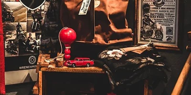 Cluttered room with various items such as a red lamp, toy cars, and framed posters on the walls.