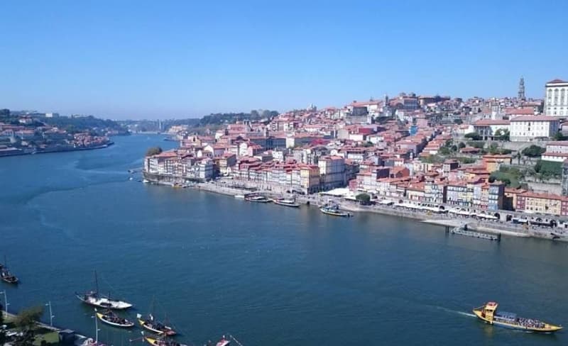 Aerial view of the historic city of Porto, Portugal, situated along the Douro River. The city is characterized by its colorful buildings, winding streets, and iconic bridges spanning the river.