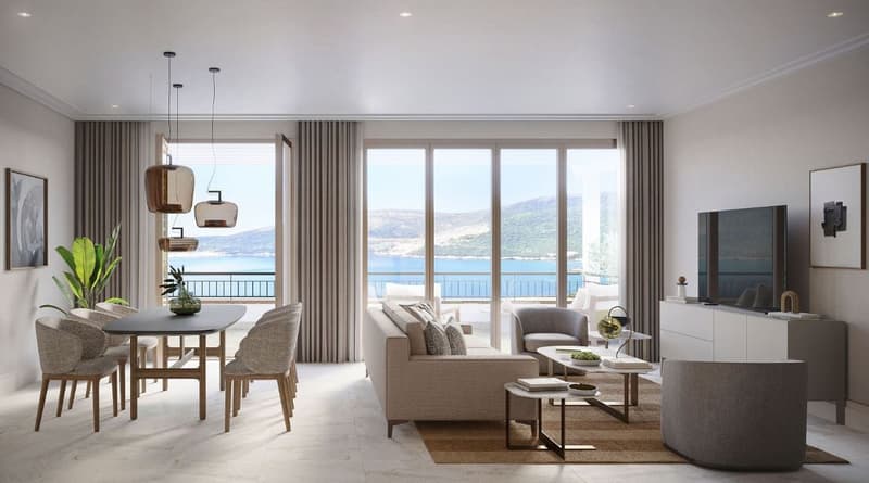 Spacious open-plan living area with large windows offering a scenic view of the lake and mountains. The room features a dining table with chairs, a comfortable sofa set, and a TV unit. The space is decorated with modern lighting fixtures and potted plants