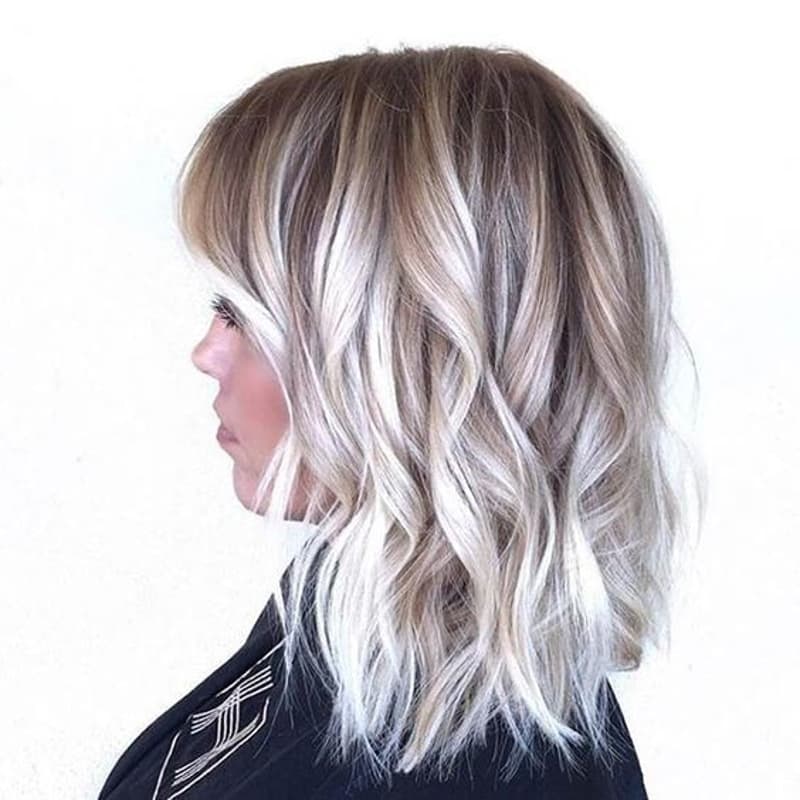 a woman with shoulder-length hair featuring a mix of light blonde and darker blonde hues, styled in a loose and wavy manner