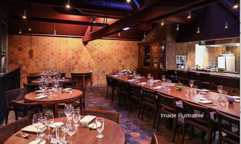 A restaurant with wooden tables and chairs, a long counter, and a hexagonal wall design.