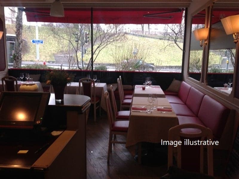 A restaurant with tables and chairs, a counter, a monitor, a lamp, and a red awning.