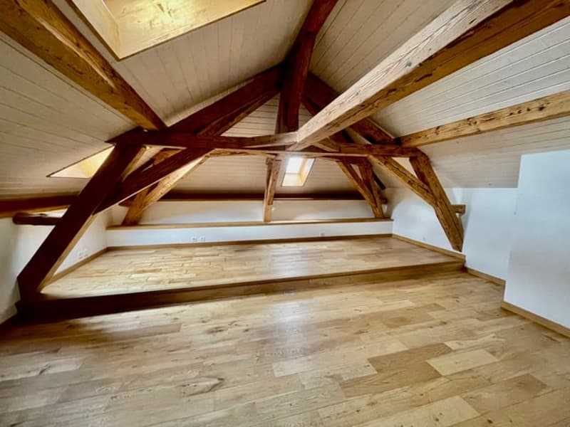 Wooden beams and trusses forming the roof structure, wooden flooring, open and spacious attic space
