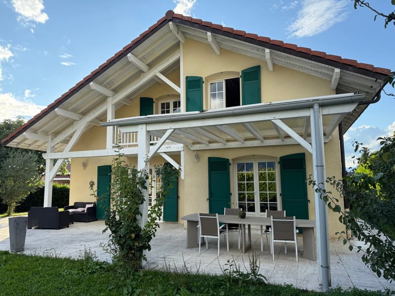 2 story yellow house, red roof, green shutters, outdoor dining table, large balcony