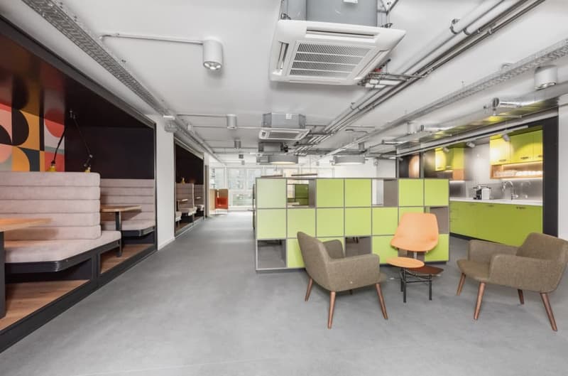 Open concept office space with modular furniture, green and gray color scheme, modern lighting and air conditioning units, lounge area with chairs and tables