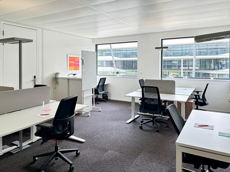 modern office with white desks, swivel chairs, large windows, whiteboard, plants