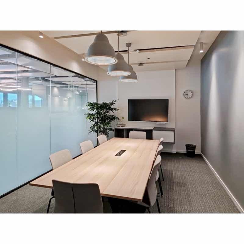 Wooden table with chairs around it, glass walls, mounted TV, trash can, and plant on the wall.