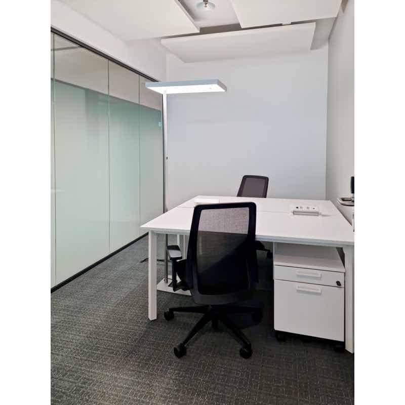 Office room with a desk, chairs, lamps, white walls, glass wall and floor.