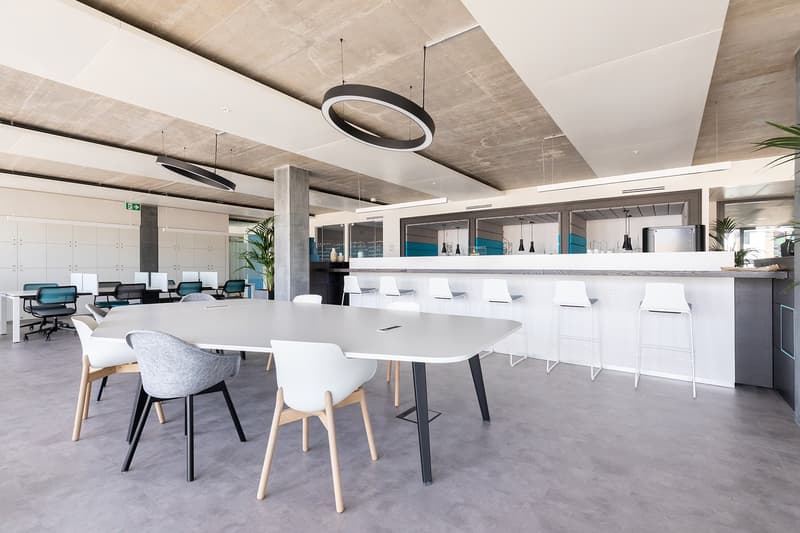 modern office room, large white table, white chairs, white counter, white cabinets, hanging lamps, gray floor