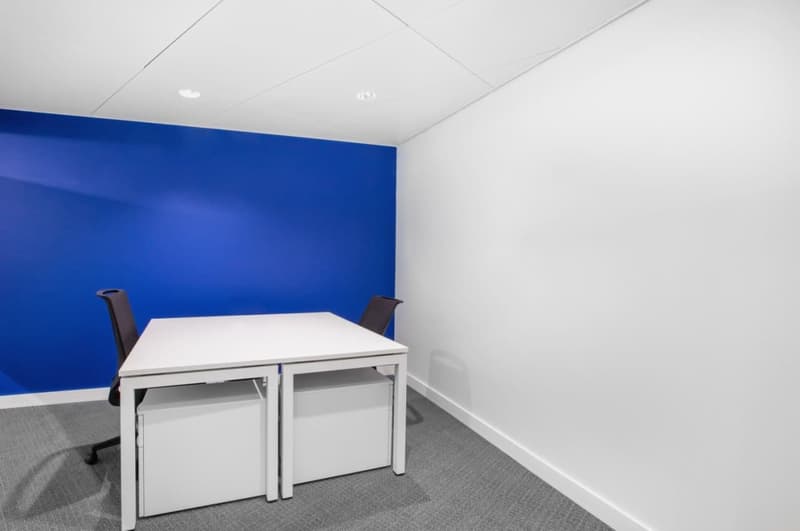 white desk, two black swivel chairs, white and blue wall
