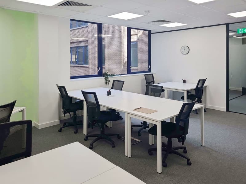 modern open layout, large windows with views, white tables, black swivel chairs, clean and organized environment