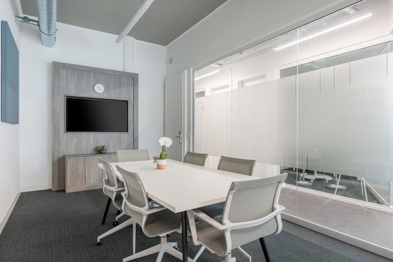 meeting room with a table, chairs, a TV, cabinet, and a clock on the wall