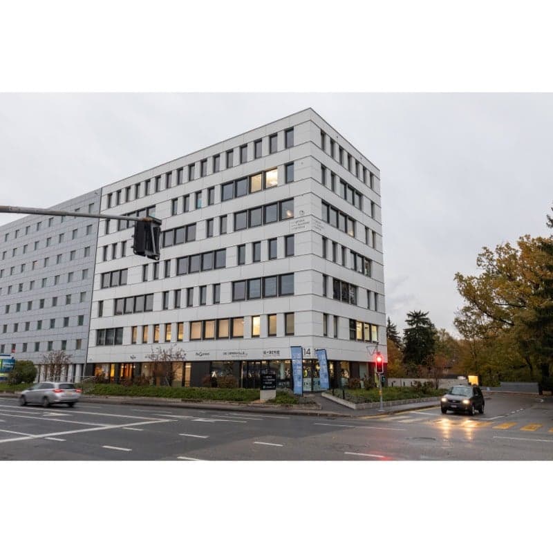 Modern office building, white exterior, multiple floors, large windows, located on a busy street