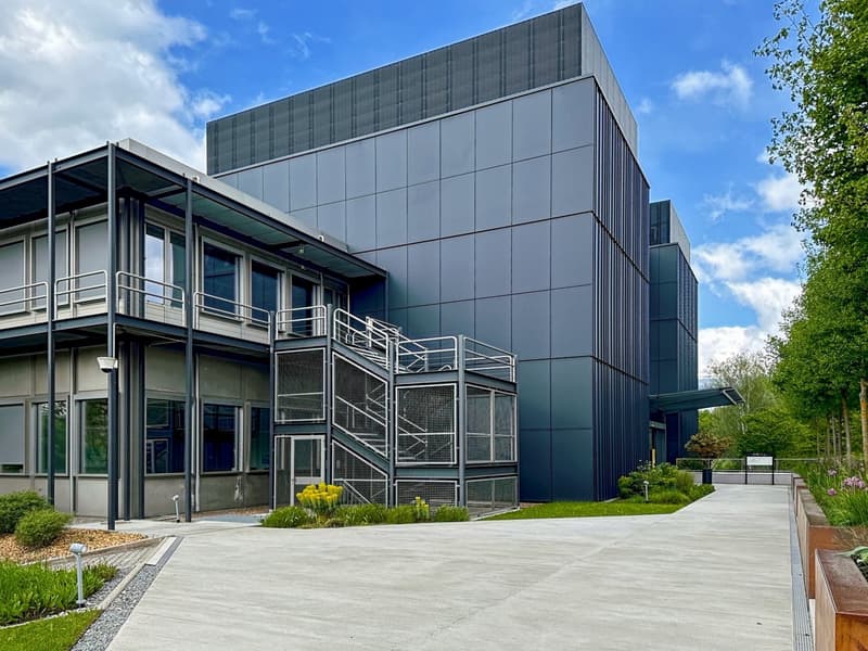 modern architectural design, two-story, metal and glass facade, gray and black colors, outdoor staircase, entrance with glass doors