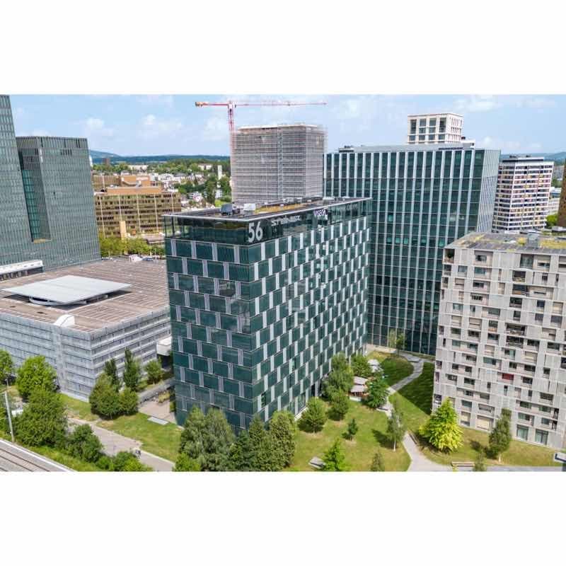 High rise office building, green windows, several buildings visible in the background