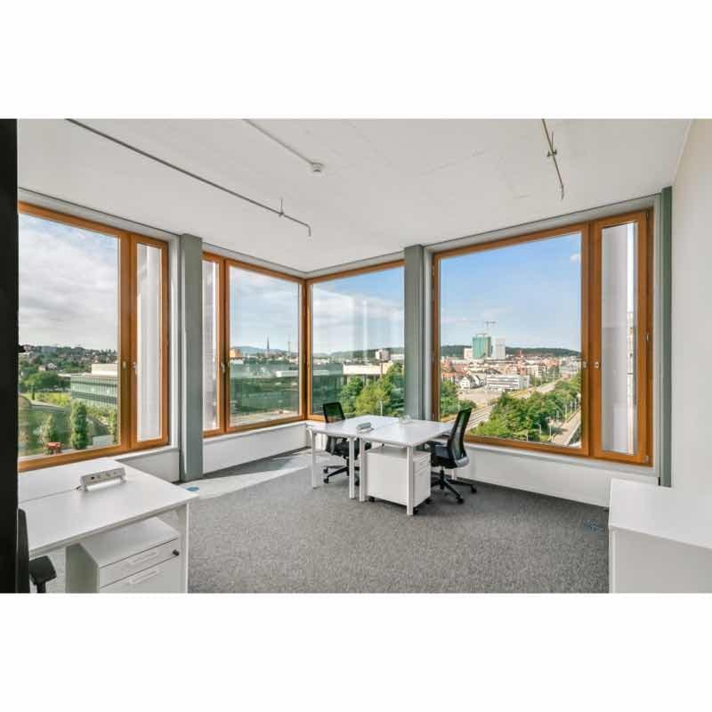 Bright office with large windows and city view, equipped with desks, office chairs, and filing cabinets, white walls and ceiling.