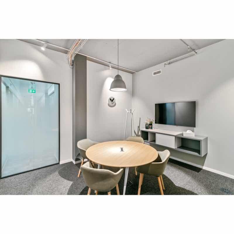Empty meeting room with table and chairs, flat screen TV, lamp, and wall shelves