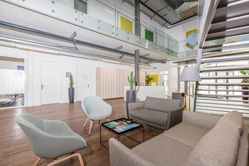 modern office space, wooden floor, gray sofas, gray chairs, small center table, lamps