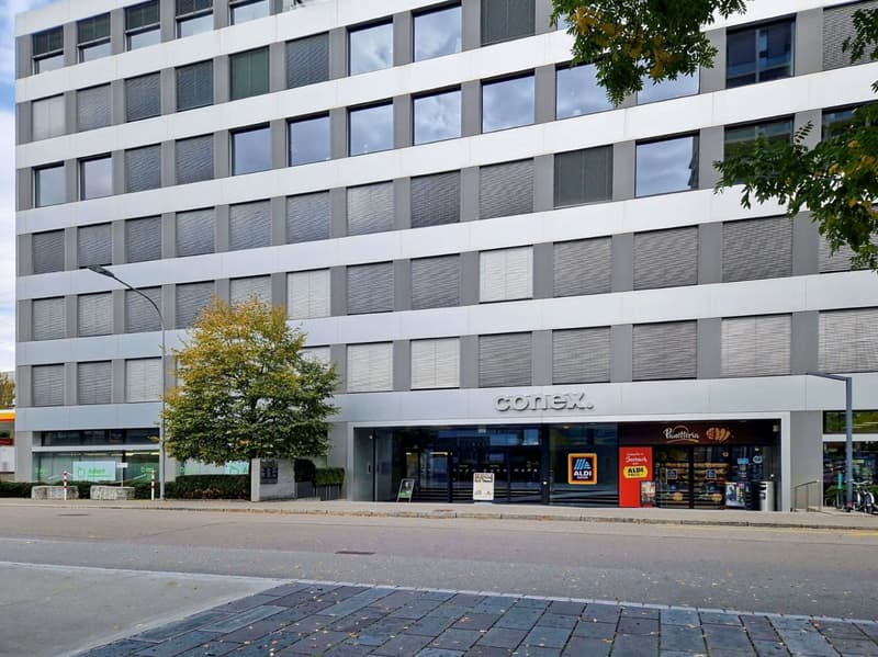 commercial building, multiple windows, 'conex' sign on facade, aldi store, parking spaces, streetlights, tree