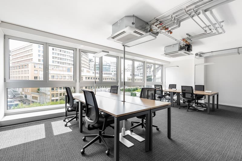 modern office room with large windows, desks, chairs, and air conditioning units