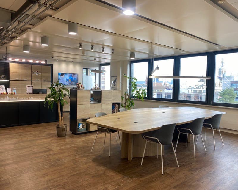 large conference room, wooden table, gray chairs, large windows, wooden floor, plants, counter, TV