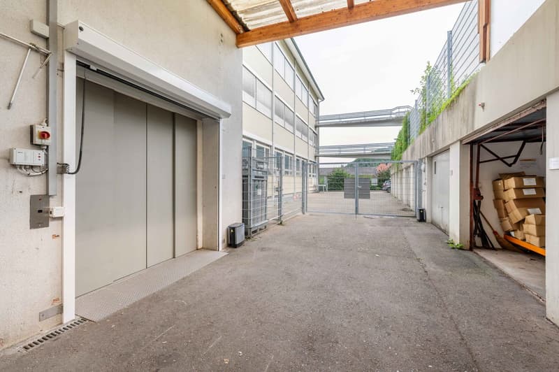 Parking area with multiple garage doors, secured by metal fences, electrical switches, large metal gate