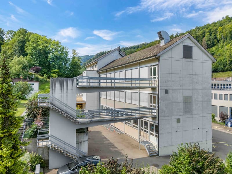 multi-level building, multiple stairs, parking lot, large window panels, raised ground floor