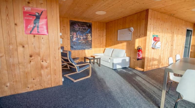 wooden walls, white couch, blue chairs, table, fire extinguisher, posters