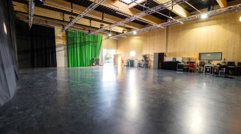 large room, concrete floor, wooden walls, green curtain, metal trusses, equipment