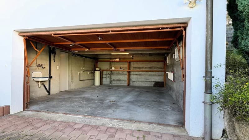 empty garage, brick pavement, white sink, wooden beams, pipe fixtures