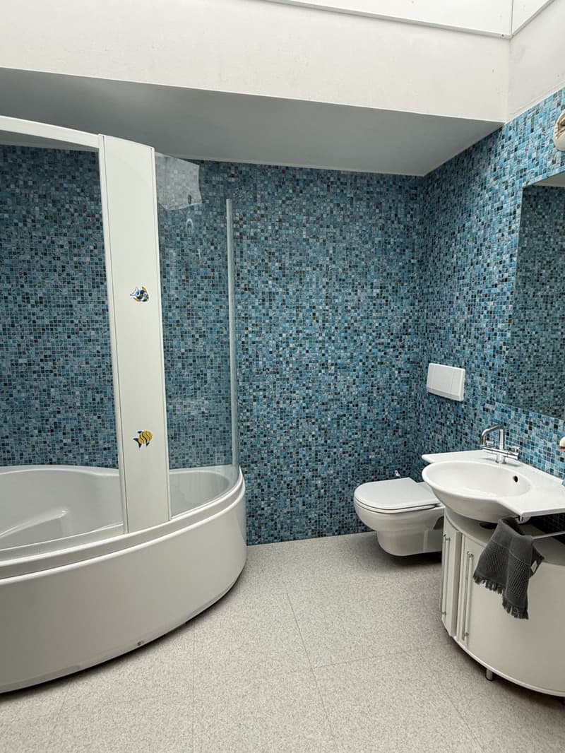 Blue tile wall, glass door, bathtub, toilet, sink, mirror