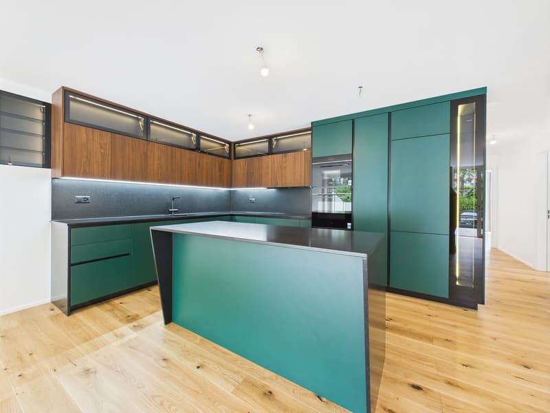 Modern kitchen with wood and teal cabinets, stainless steel appliances, and a central island with a countertop. The kitchen has a sleek and contemporary design with ample storage and workspace.
