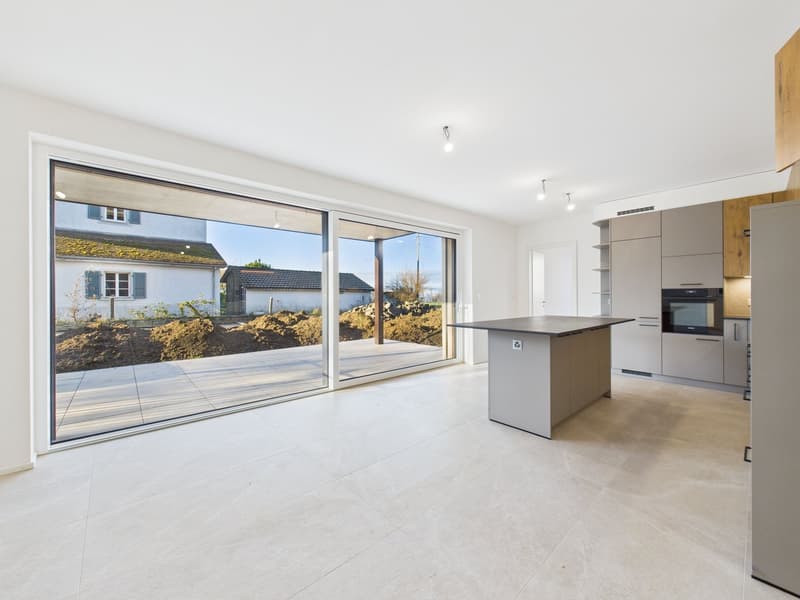 Open kitchen with central island, built-in oven, large sliding doors leading to a terrace, white flooring, and modern fixtures.