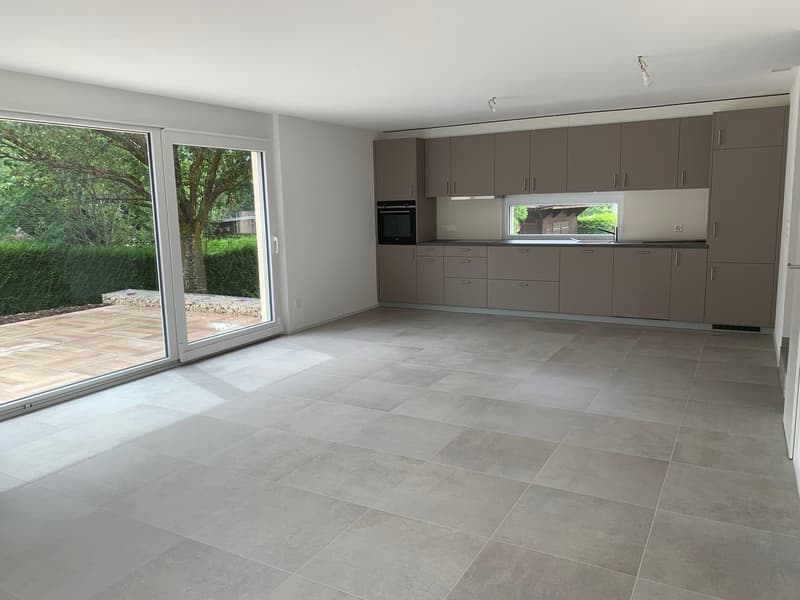empty room with tiled floor, sliding glass doors, kitchen with oven, countertops, sink, and cabinets
