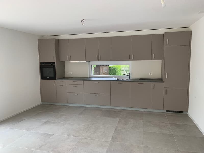 modern kitchen with large windows, gray cabinets, tiled floor, built-in oven, integrated dishwasher, stainless steel sink