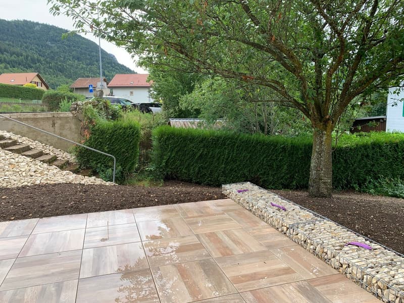 stone paving, stone wall, rock bed, hedges, trees, background with houses and mountains