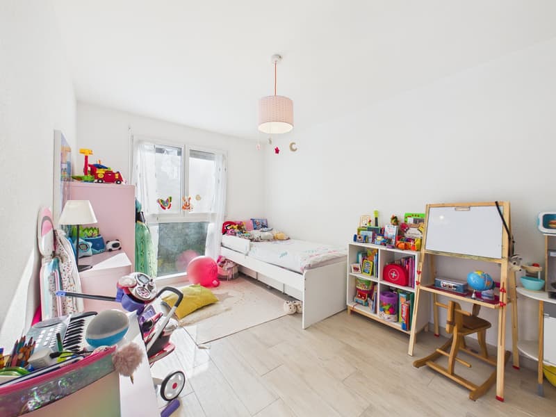 A children's room with a white bed, white cabinets, white floor, white walls, wooden floor, whiteboard, storage box, a pink balloon, and toys