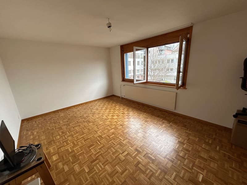 empty room, wooden parquet floor, white walls, large window, radiator, monitor on desk